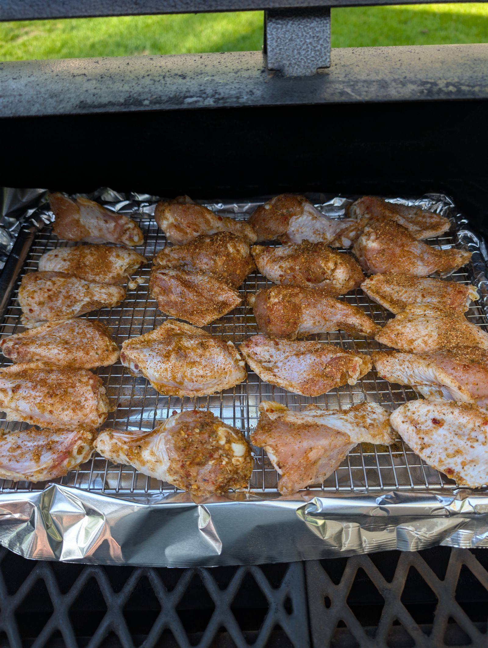 Seasoned chicken wings arranged on a wire rack inside a pellet grill